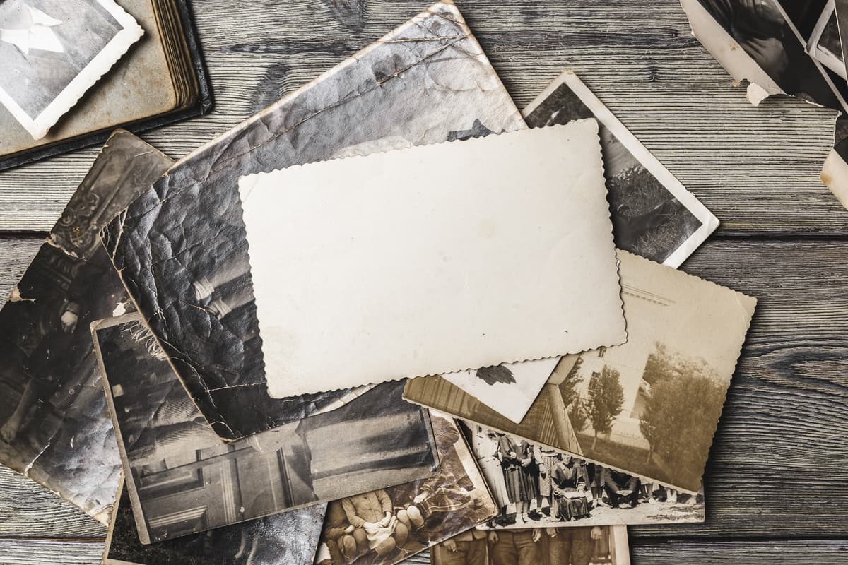 Old family photographs spread on a wooden table in soft, warm light